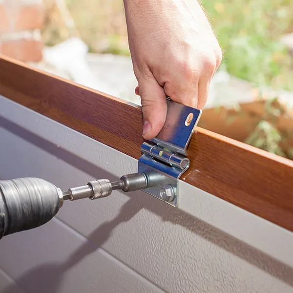 Technician installing a new wood-look garage door panel