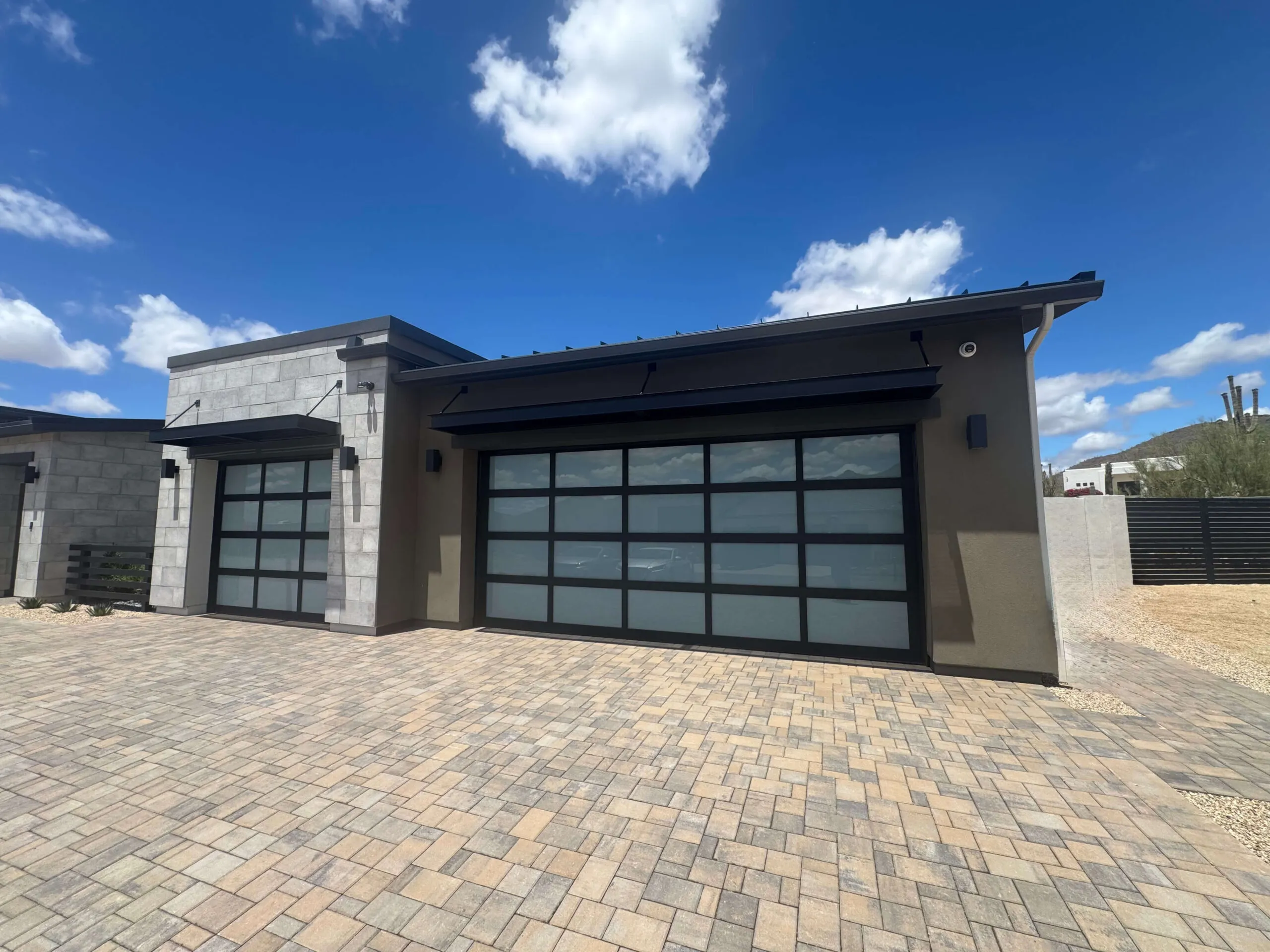Modern glass and black aluminum garage doors on a desert home
