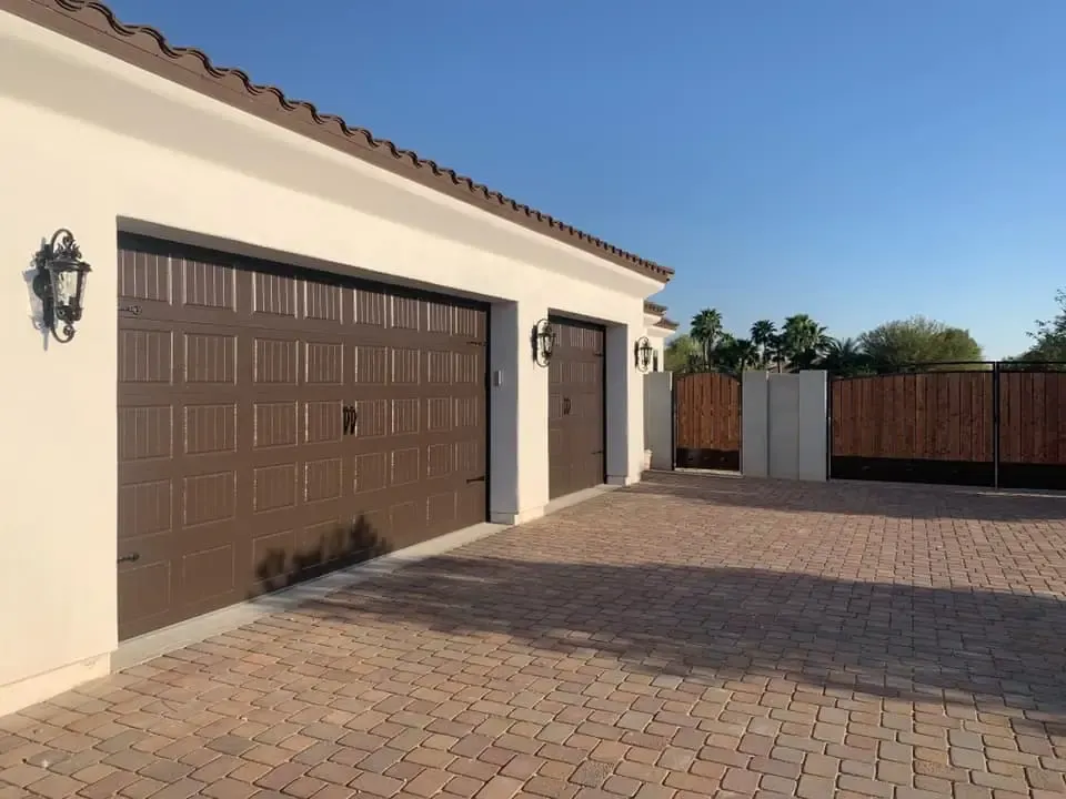 Brown residential garage doors on a home with a paver driveway